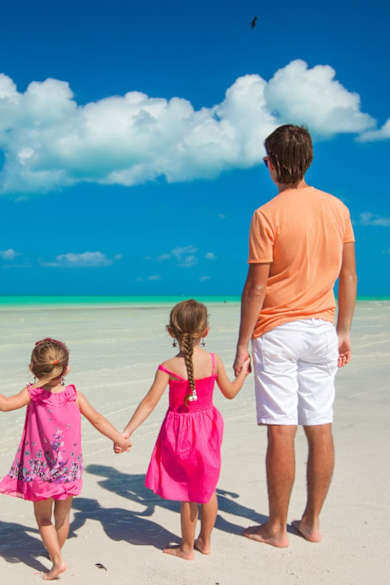 Eine Familie steht an einem Strand und blickt auf das Meer.