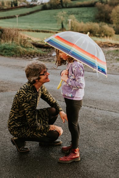 Eine Großmutter kniet vor ihrer Enkelin, die einen Regenschirm hält. © Catherine Falls Commercial/Moment via Getty Images
