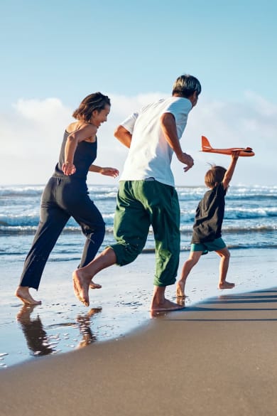 Eltern rennen ihrem Kind am Strand hinterher.