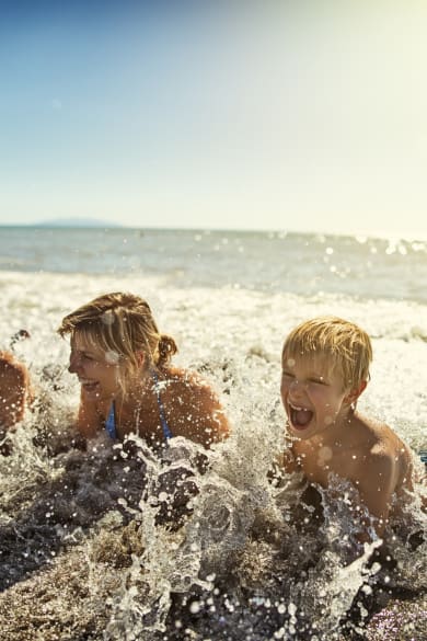 Familie liegt am Strand und planscht in Meereswellen in der Toskana, Italien