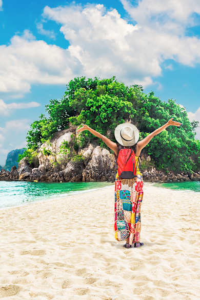 Eine Frau steht mit ausgebreiteten Armein an einem Strand