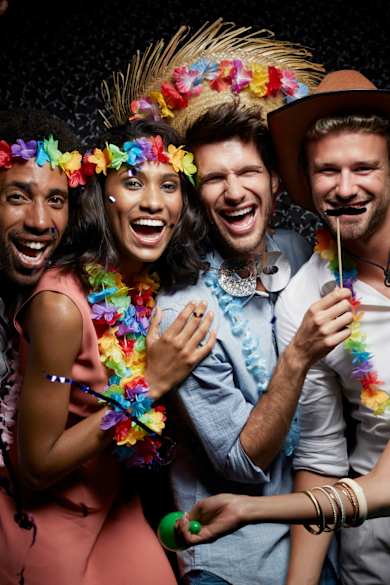 Lachende Freunde tragen Girlanden in einem Nachtclub. © Morsa Images/DigitalVision via Getty Images