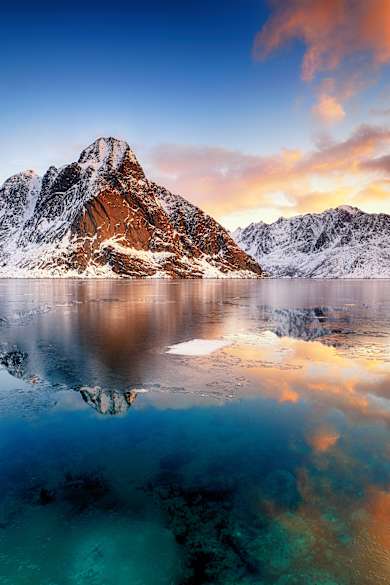 Schneebedeckte Berge spiegeln sich im Eiswasser.