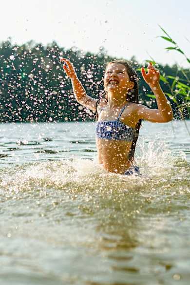 Ein Mädchen planscht im Wasser.