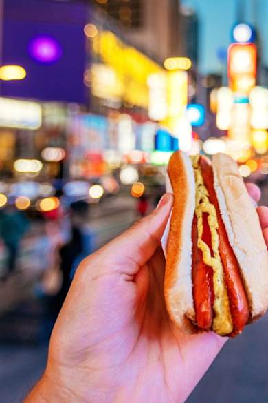 Ein Mann isst ein Hot Dog am Times Square in New York.
