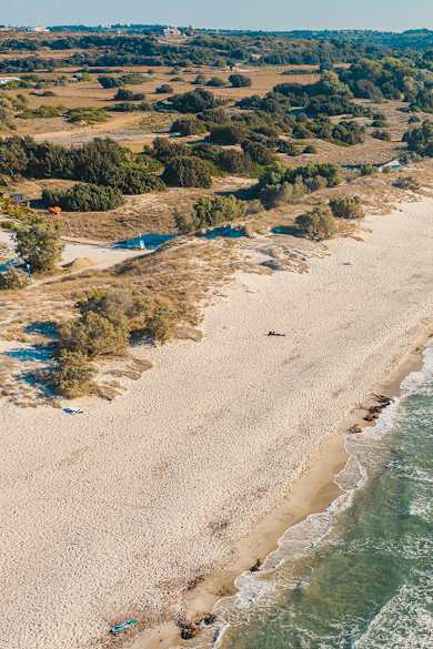 Ein langer Sandstrand in einer ländlichen Umgebung, der von Kitesurfern genutzt wird