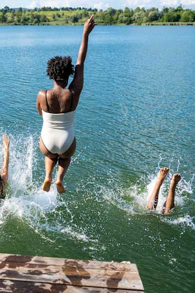 Mehrere Personen springen in das Wasser eines Sees