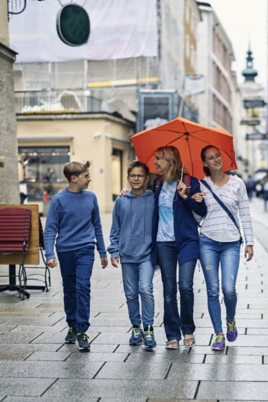 Eine Mutter läuft mit ihren Kindern im Regen durch Salzburg, Österreich. © Imgorthand/E+ via Getty Images