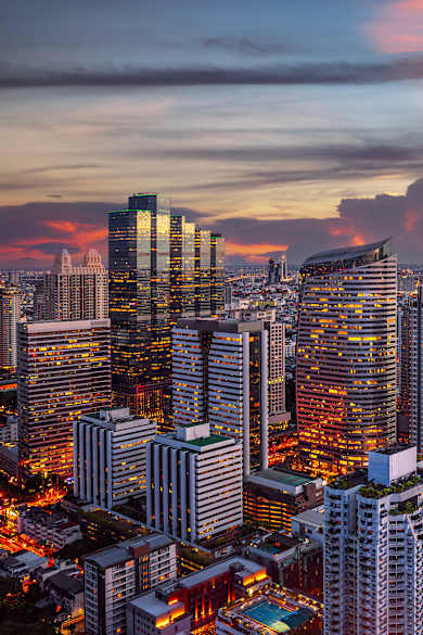 Blick auf eine Skyline bei Sonnenuntergang. In den zahlreichen Hochhäusern glitzern die Lichter der Stadt
