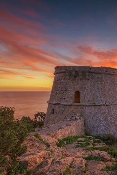Ein historischer Turm bei Dämmerung mit einer Insel im Hintergrund