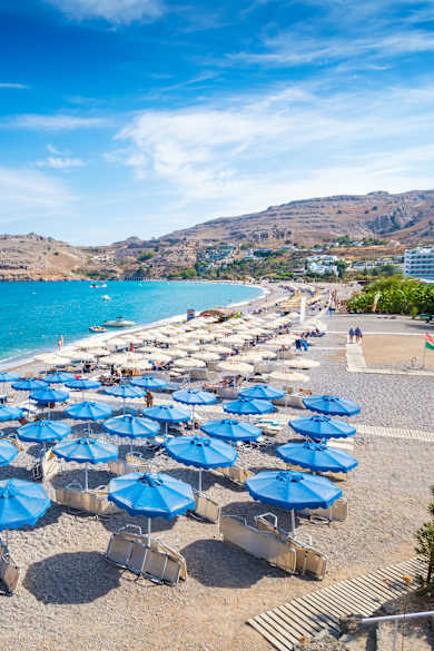 Ein weiter Strand mit blauen Sonnenschirmen
