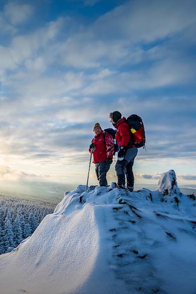 Zwei Wanderer stehen auf einem schneebedeckten Gipfel.