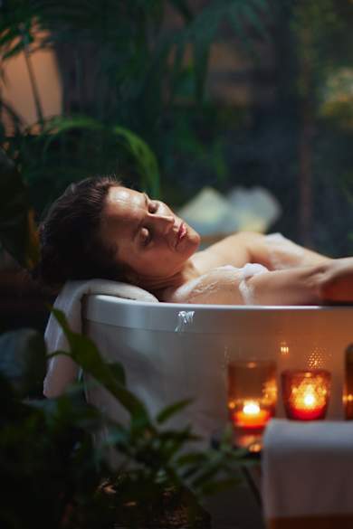 Frau liegt bei Kerzenschein in Badewanne und entspannt.