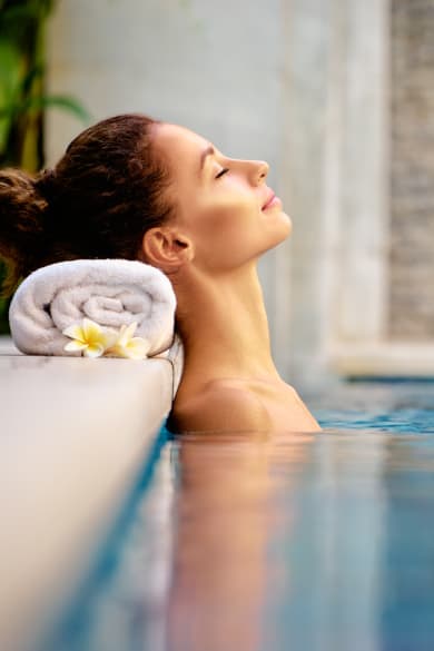 Frau liegt im Pool und macht Wellnessurlaub.
