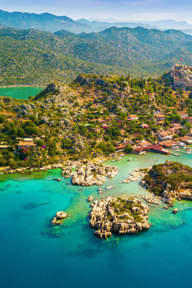 Blick auf die Weite der Türkischen Riviera mit grüner Landschaft. Im Vordergrund ist das blaue Meer zu sehen.