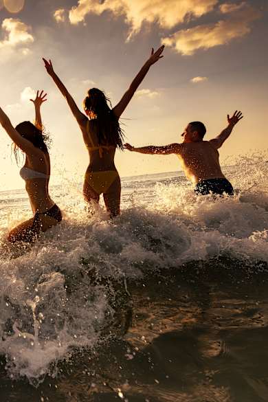 Eine Gruppe Frauen und Männer feiert eine Party am Strand im Meer.