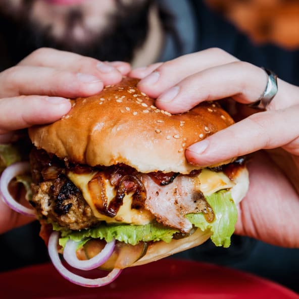 Eine Person hält einen Hamburger in den Händen.