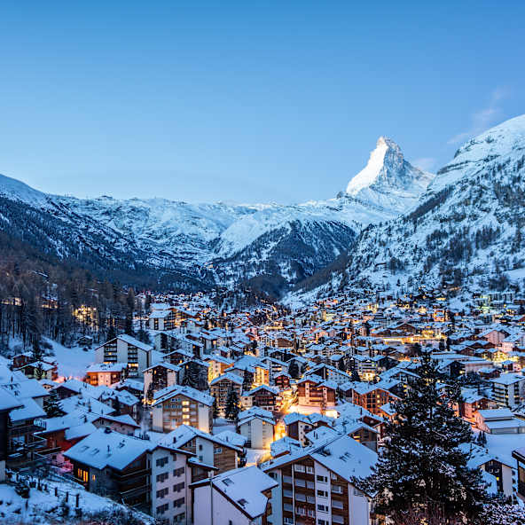 Eine verschneite Stadt in einem Tal mit dem Matterhorn im Hintergrund.