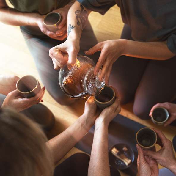 Frau gießt in einer Runde Tee ein.