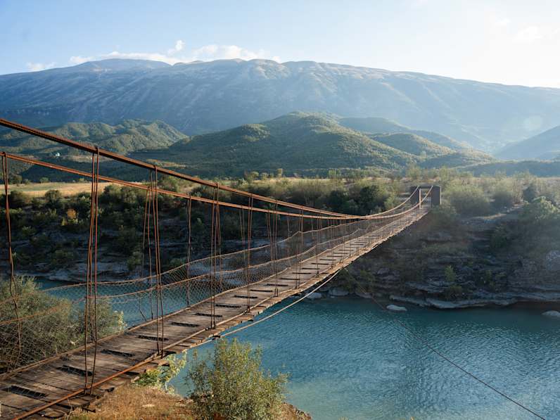 Eine hölzerne Hängebrücke verbindet zwei Landstücke miteinander