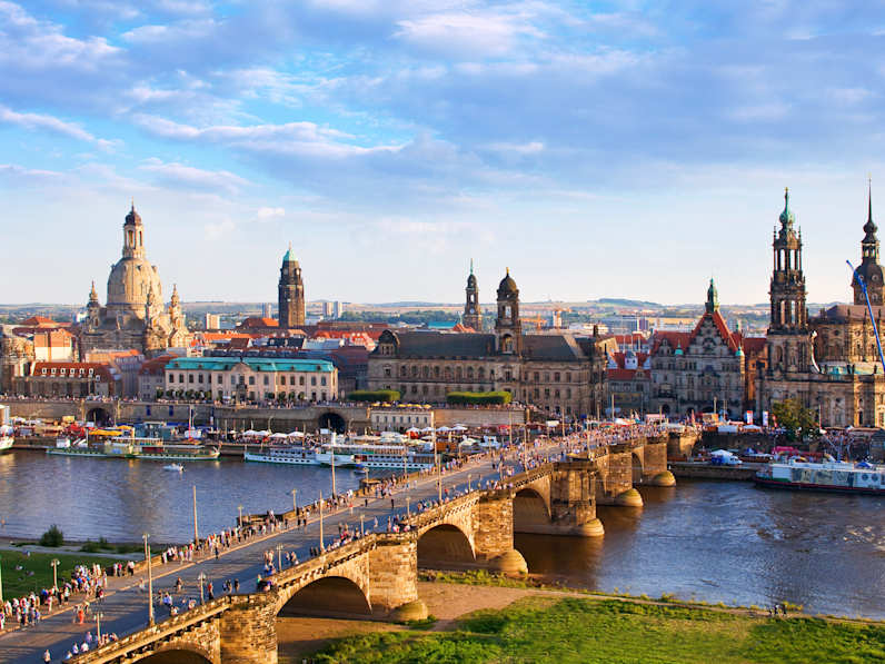 Blick auf eine Brücke und die Altstadt von Dresden mit zahlreichen Türmen und Kuppeln