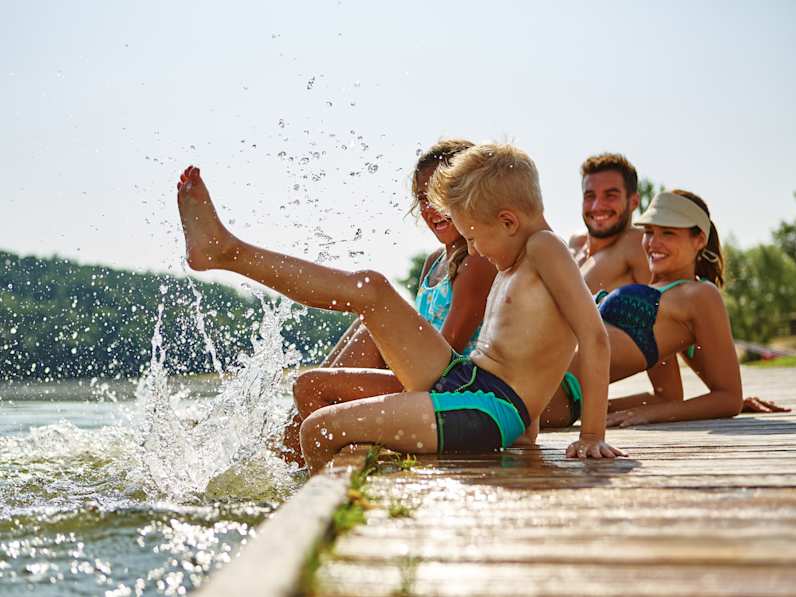 Eine Familie sitzt auf einem Steg am See