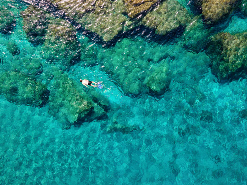 Ein Mann, der im Sommer im smaragdgrünen Wasser der Ägäis auf der griechischen Insel Andros © iStock.com/SHansche