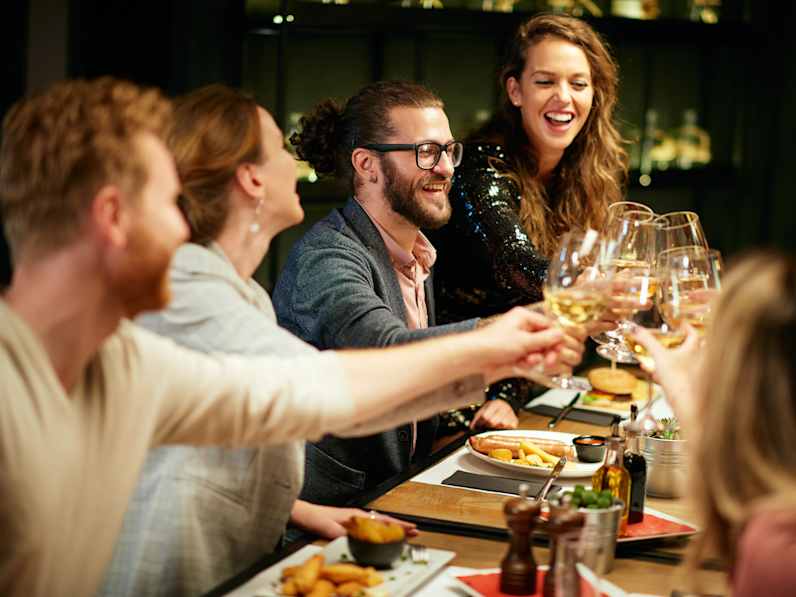 Eine Gruppe FreundInnen stoßen an einem Restauranttisch an
