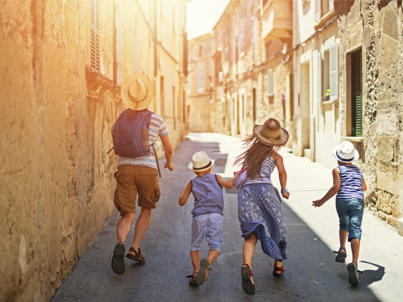 Familie mit zwei Kindern rennt durch die Altstadt von Mallorca © iStock.com/Imgorthand