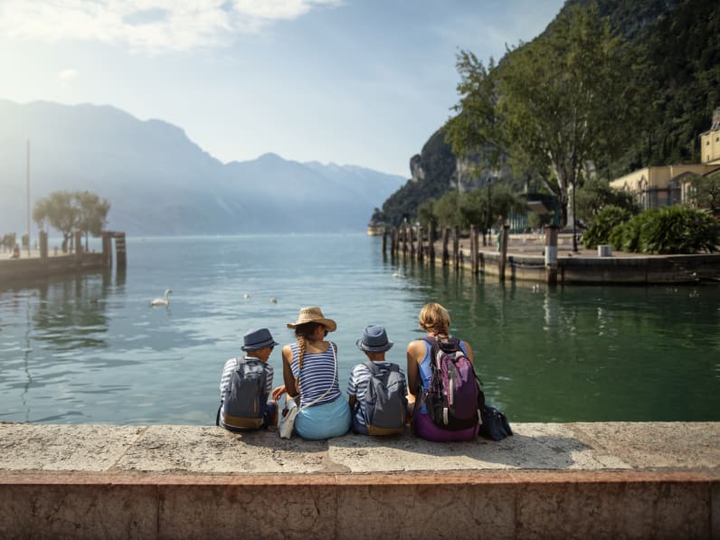 Familie sitzt am Hafen von Riva del Garda und schaut auf den Gardasee © iStock.com/1061876216