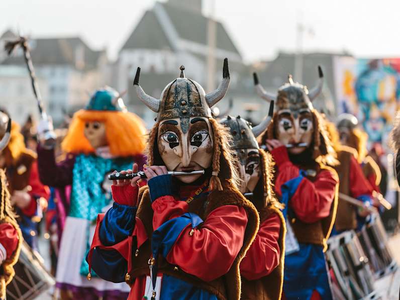 Ein verkleideter Karnevals-Verein zieht durch Basel und spielt auf Querflöten.