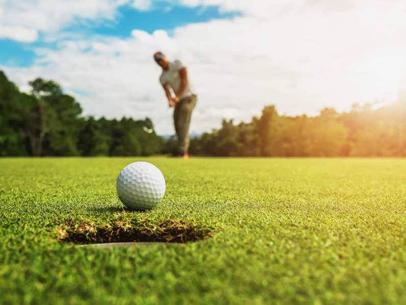 Golfer beim Putt – der Ball kurz vor dem Loch