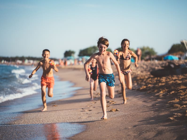 Kinder laufen und schießen mit Wasserpistolen am Strand © iStock.com/martin-dm