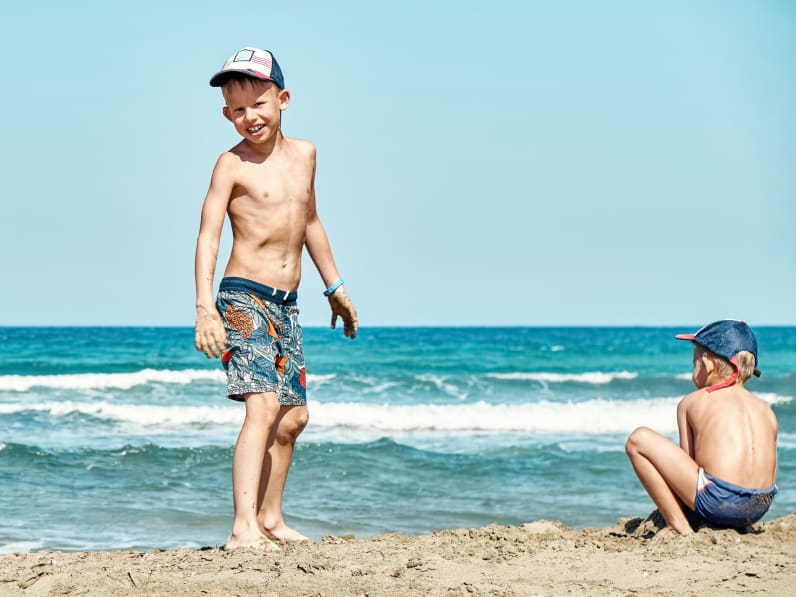 Lustige fröhliche kleine Brüder spielen an Sandstrand am Meer ©iStock.com/timltv