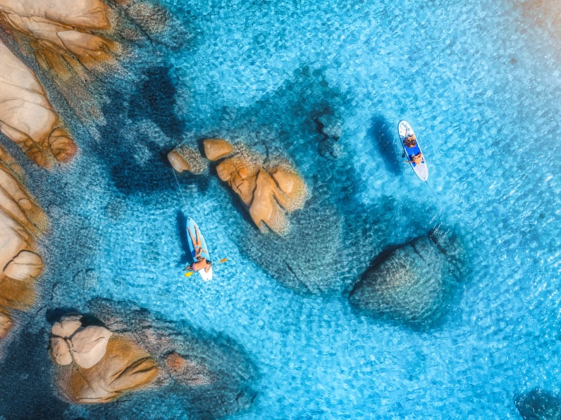 Menschen auf schwimmendem Kanu im transparenten azurblauen Wasser, Insel Sardinien © iStock.com/den-belitsky