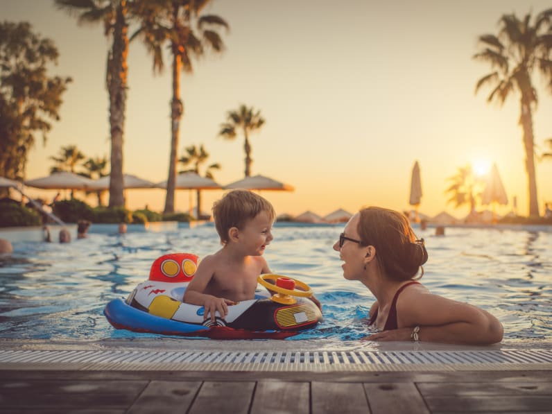 Mutter mit ihrem Kind im Pool beim Sonnenuntergang © iStock.com/ArtMarie