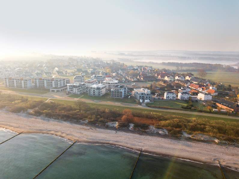 Drohnenaufnahme Strand und Städtchen im Nebel von oben.