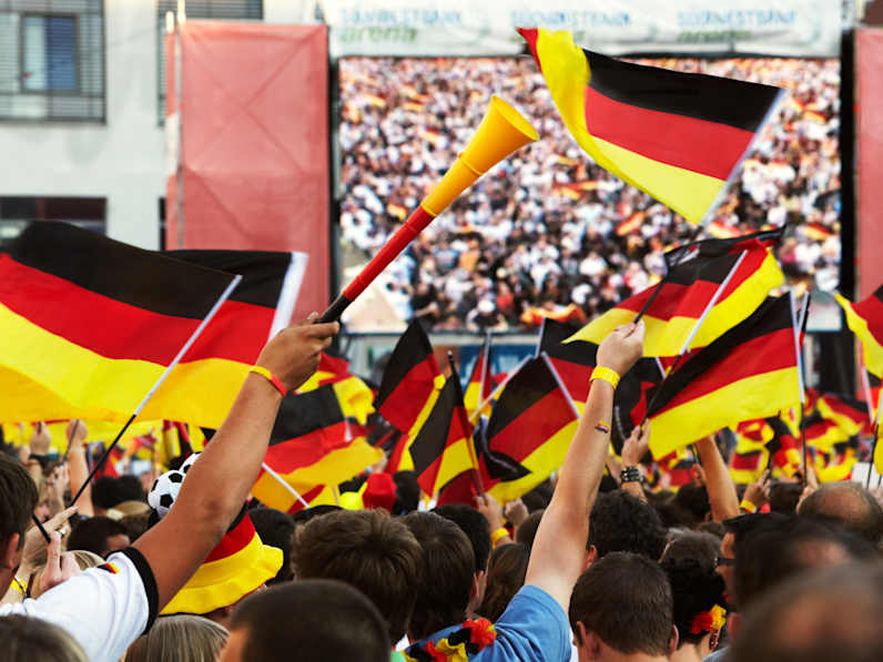 Fans mit Deutschlandflaggen vor einem großen Bildschirm