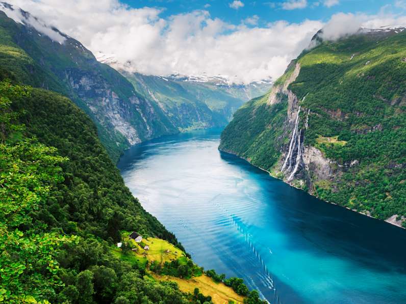 Ausblick auf den Sunnylvsfjorden Fjord in Norwegen mit grünen, bewaldeten Berghängen und Wasserfällen.