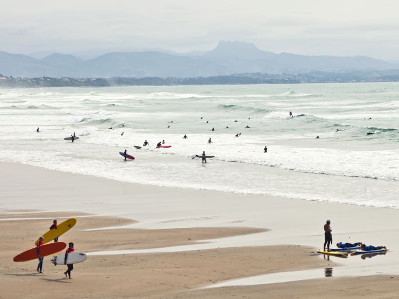 Surfer laufen am Strand und reiten die Wellen © iStock.com/peeterv