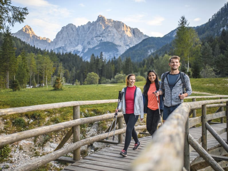 Zwei Frauen und ein Mann laufen über eine Brücke © iStock.com/AzmanL