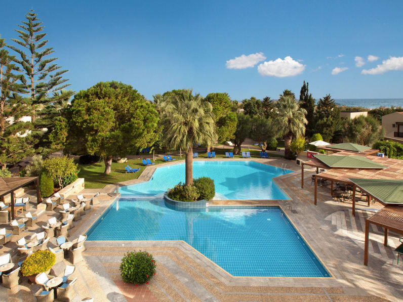 Blaues Poolbecken, Sitzmöglichkeiten, Sonnenschutz und Garten im Hotel Cretan Malia Park auf Kreta in Griechenland