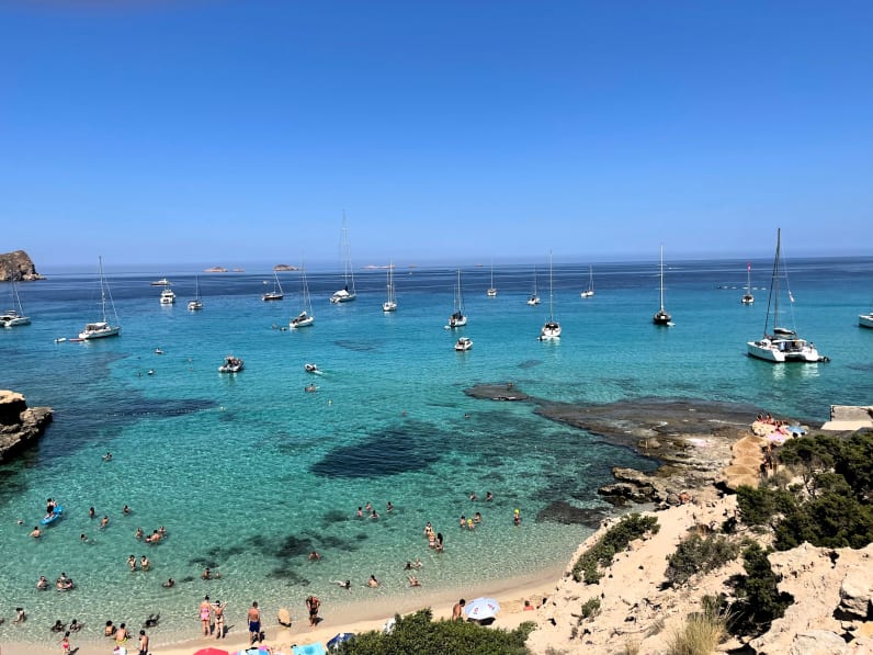 Boote und Touristinnen an der Cala Comte, Ibiza, Spanien