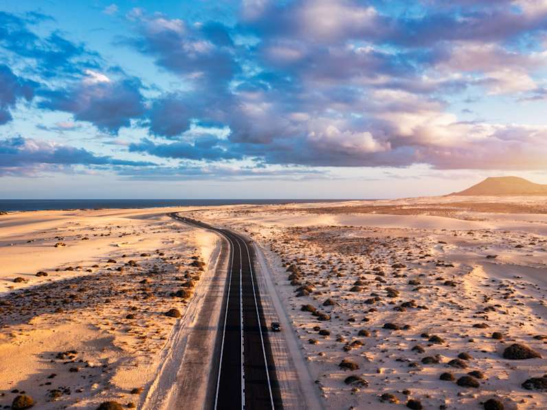 Blick auf die Straße, die durch die Dünenlandschaft bei Corralejo, Fuerteventura, führt