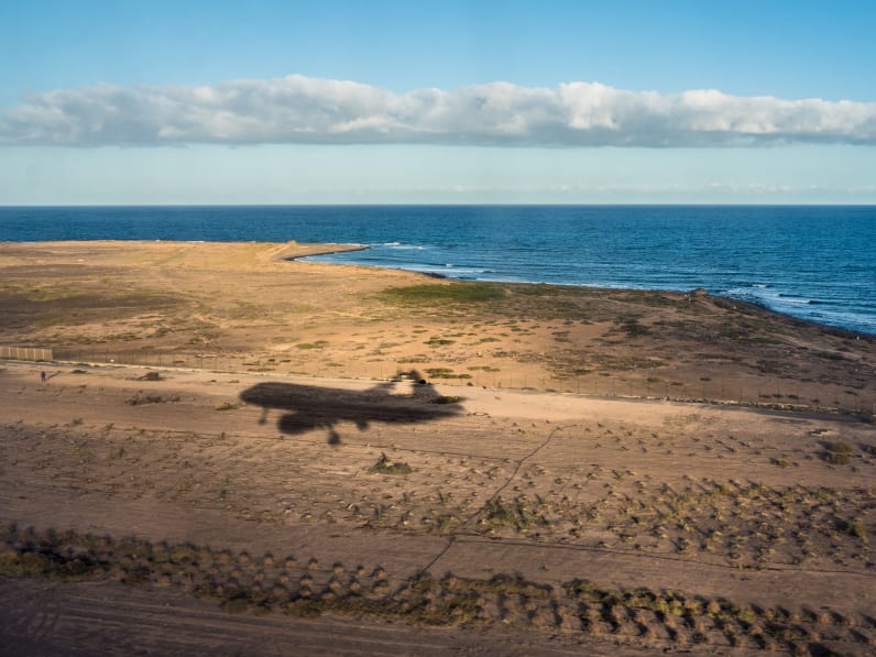 Der Schatten eines Flugzeugs über einer Küste.