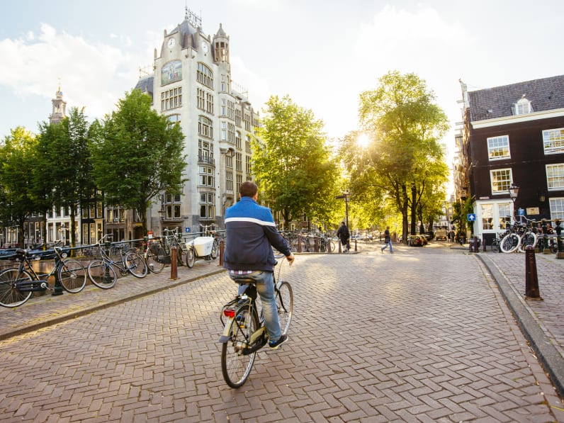 Ein Mann fährt mit dem Fahrrad über eine Brücke in Amsterdam.
