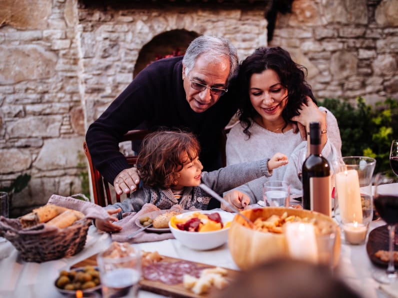 Ein Mann mit seiner Tochter und seinem Enkel beim Essen in Italien. © wundervisuals/E+ via Getty Images