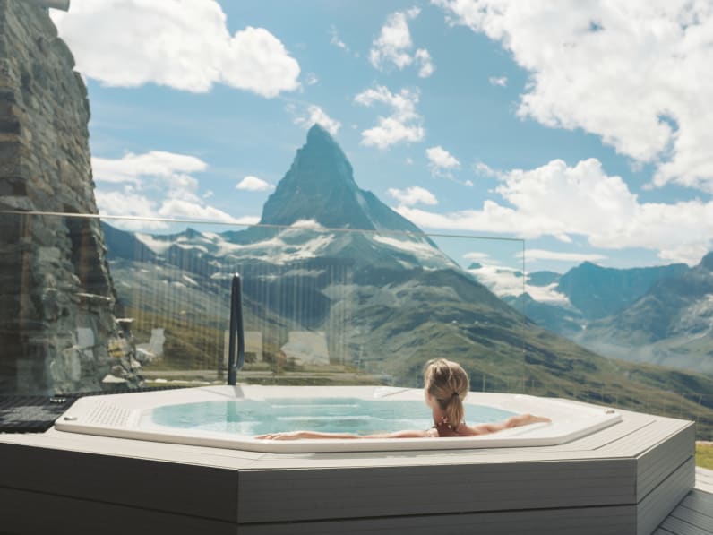 Eine Frau schaut von einem Whirlpool auf die Berge.