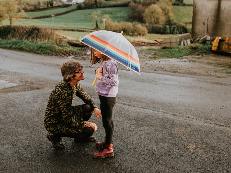 Eine Großmutter kniet vor ihrer Enkelin, die einen Regenschirm hält. © Catherine Falls Commercial/Moment via Getty Images