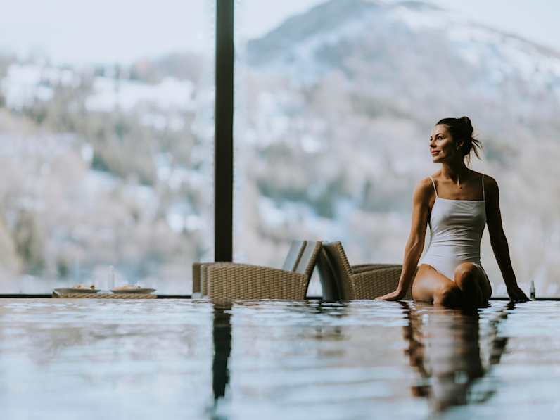 Eine Frau sitzt am Rand eines Pools